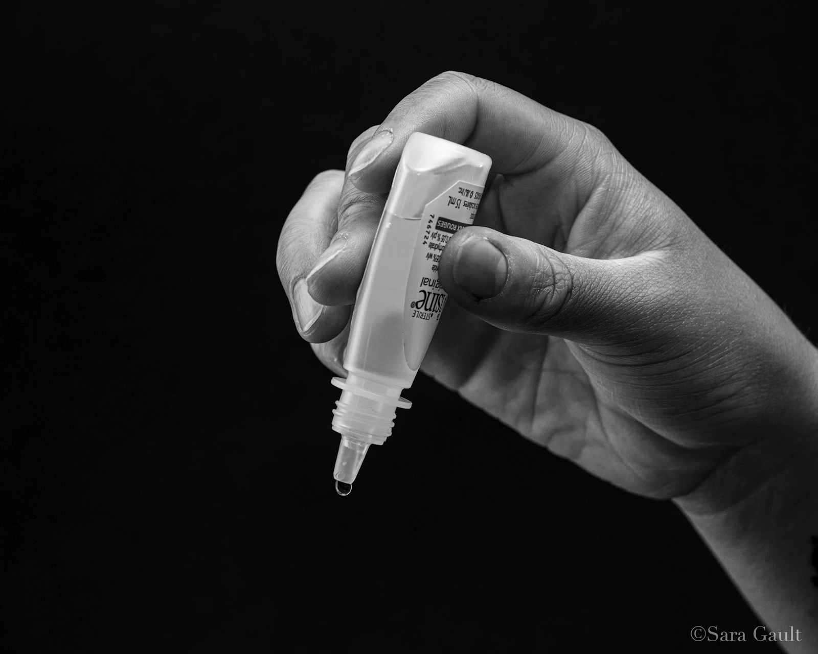 Hand holding eye drops, ready to administer