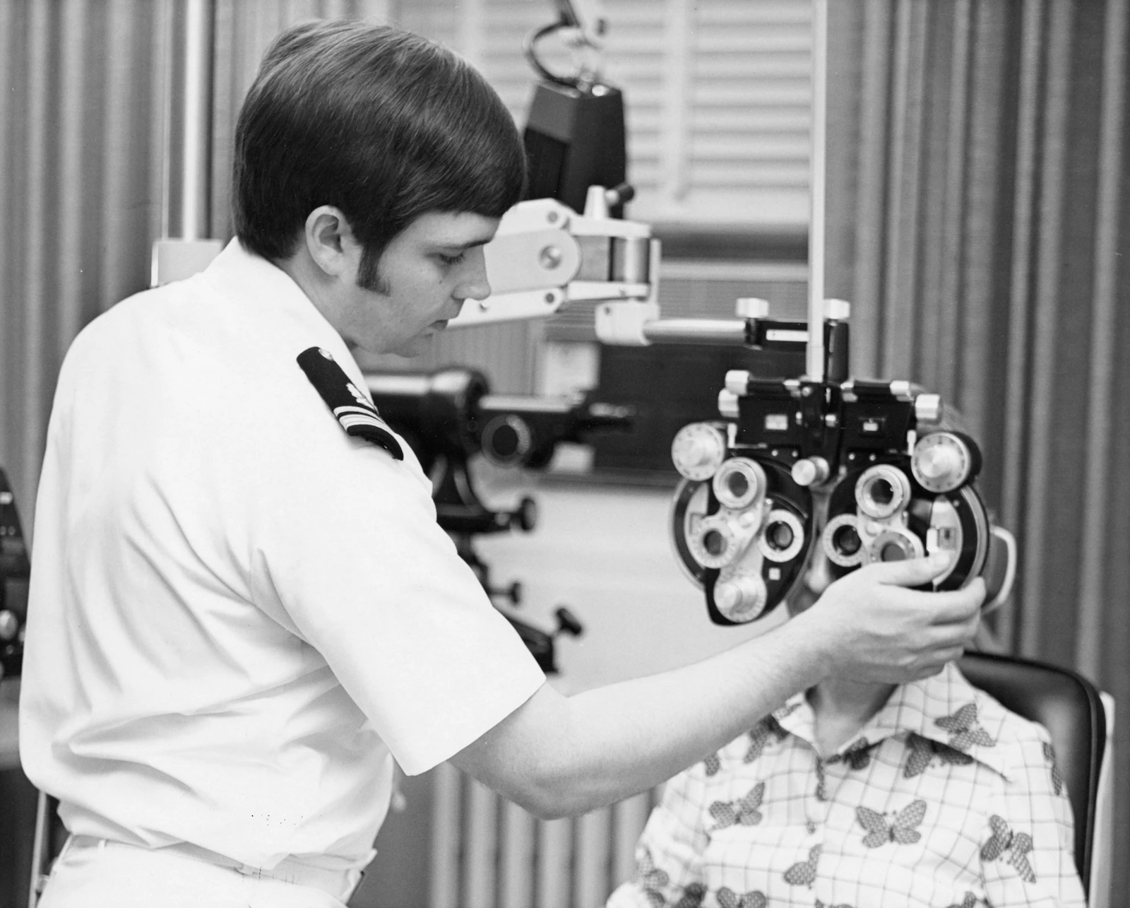 An optometrist examines a patient's eyes with a phoropter