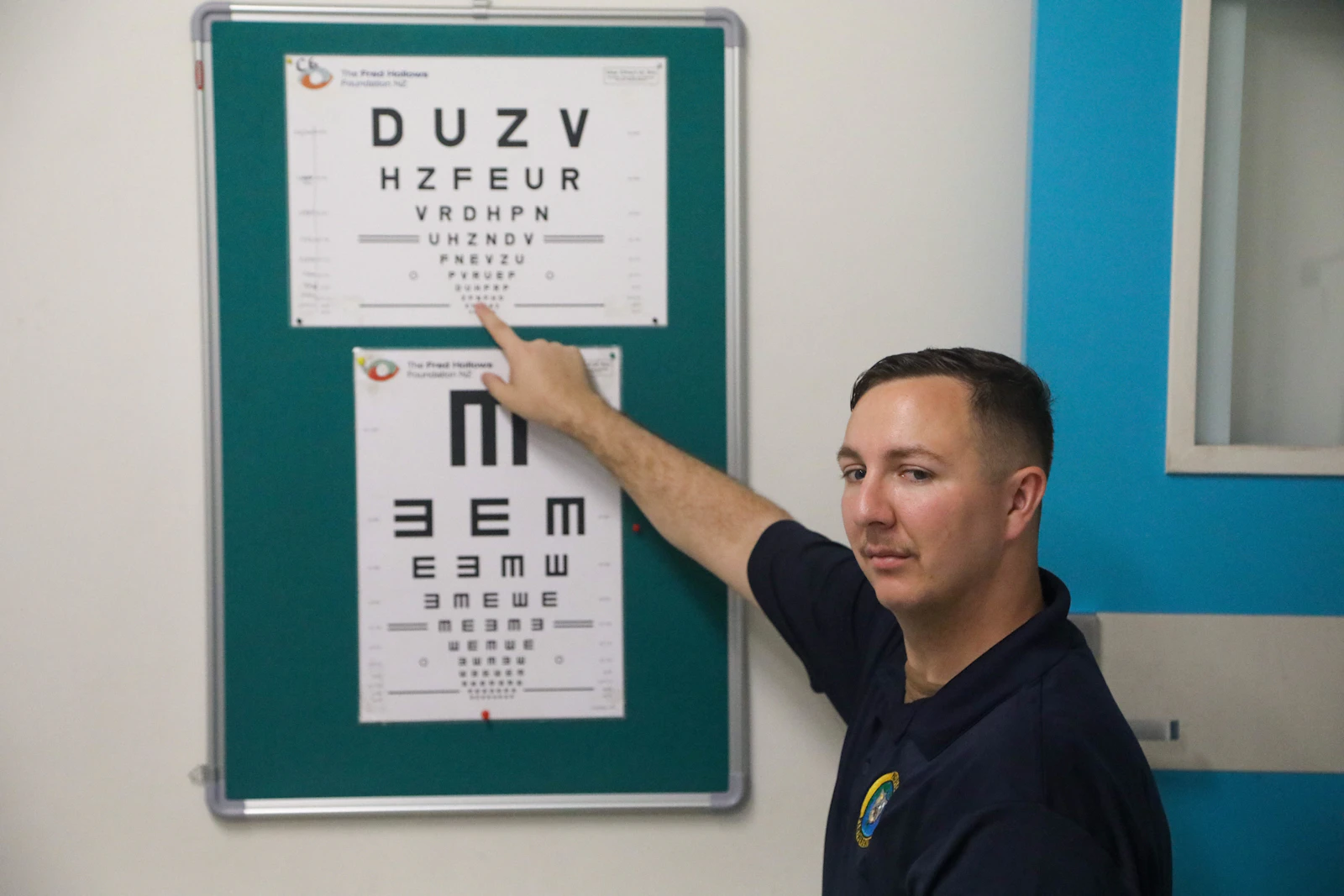 Man points to an eye chart during an exam
